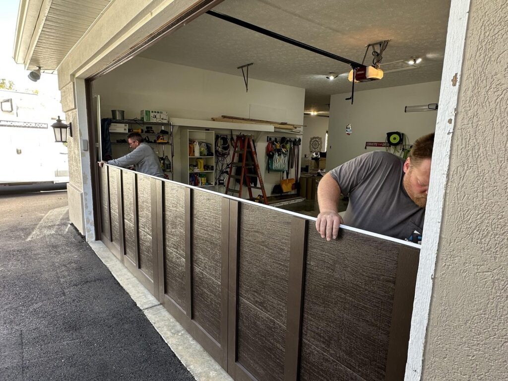 Two Fairmount Door technicians install a new wood-look garage door