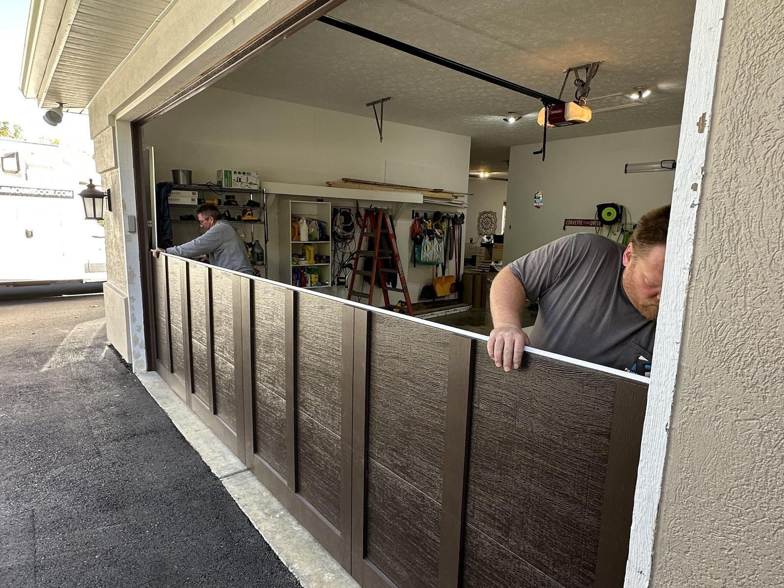 Two Fairmount Door technicians install a new wood-look garage door